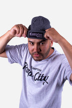 Homem ajustando o Gorro Collab Starter x Compton 310 Cinza, com estilo streetwear e patch bordado.